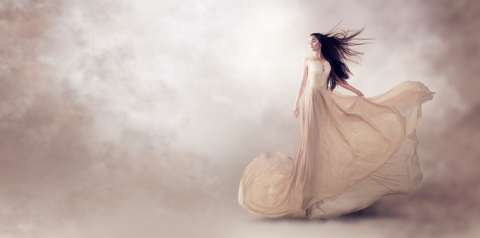 Frau in einem fließenden, champagnerfarbenen Abendkleid